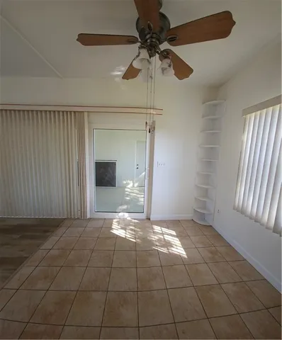 a view of an empty room and window and chandelier fan