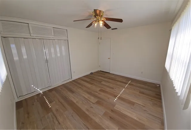 a view of a room with wooden floor closet and a ceiling fan