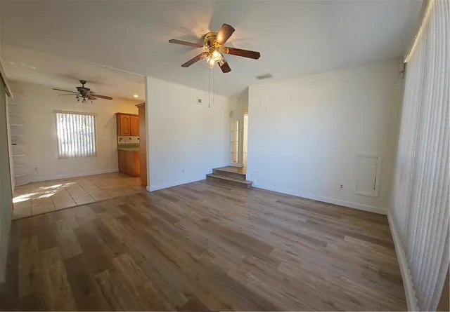a view of empty room with wooden floor and fan