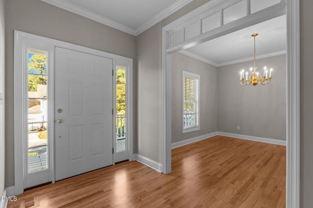 a view of a livingroom with a chandelier wooden floor and a kitchen