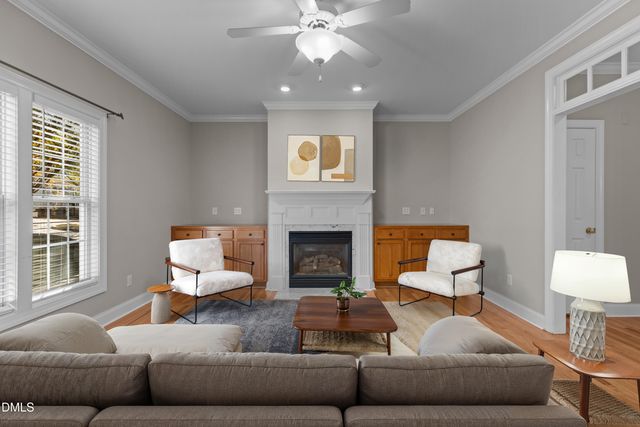 a view of an empty room with wooden floor fireplace and a window