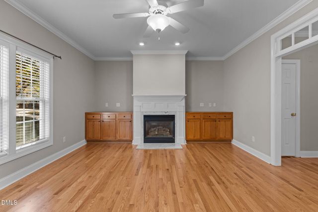 an empty room with wooden floor cabinet and windows