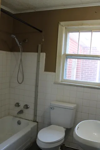 an empty room with wooden floor and windows with curtains