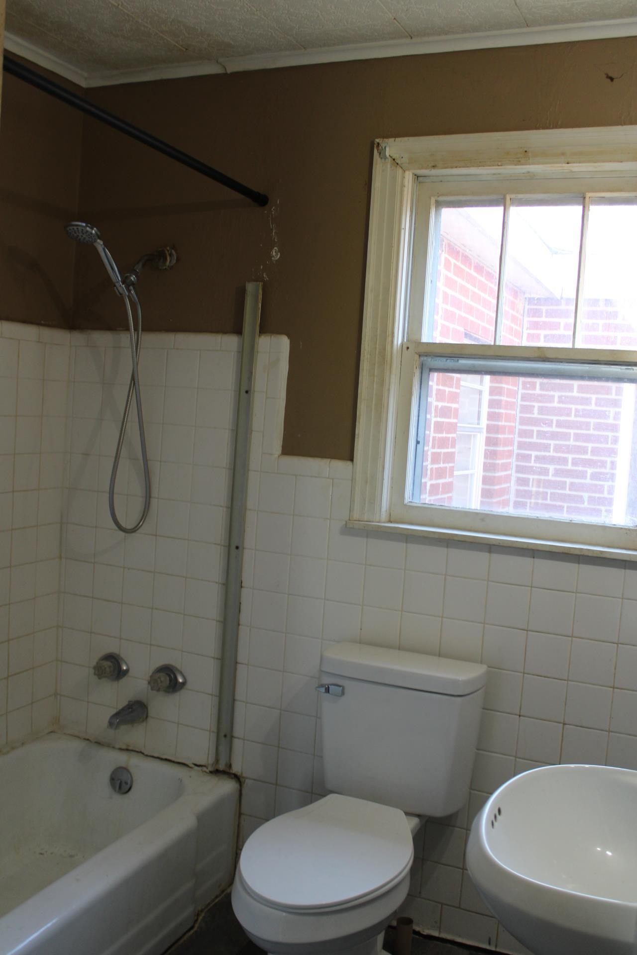 1027 Lynn School Road Ripley, TN 38063 - Photo 16 of 26 a white toilet and a bath tub sitting next to a window
