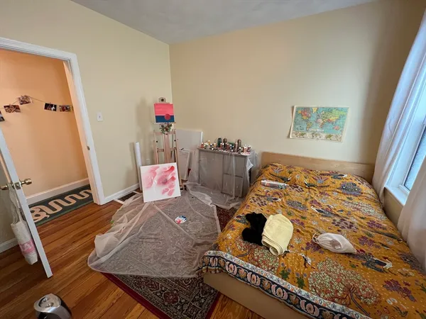 a large bed sitting in a bedroom next to a window with wooden floor