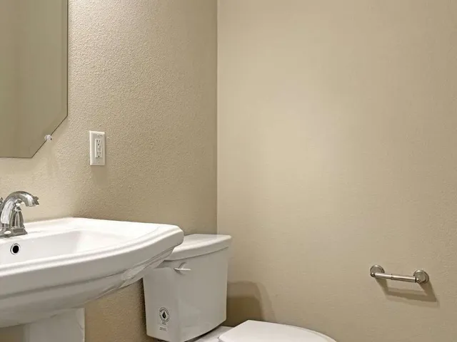 a bathroom with a sink a toilet a mirror and shower curtain