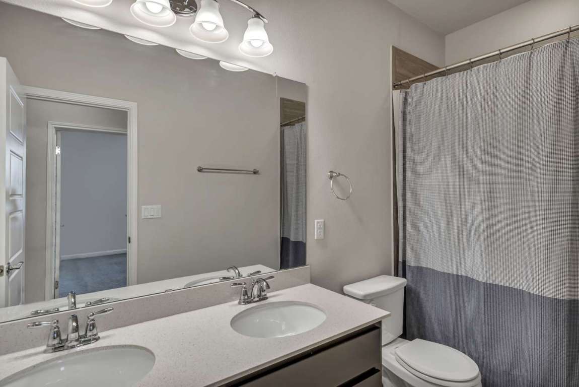 13800 Lyndhurst Street, Unit 223 Austin, TX 78717 - Photo 19 of 40 a bathroom with a sink a toilet a mirror and shower curtain