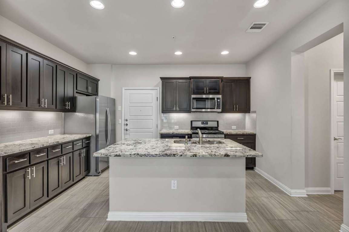 13800 Lyndhurst Street, Unit 223 Austin, TX 78717 - Photo 10 of 40 a large kitchen with stainless steel appliances granite countertop a stove a sink and a refrigerator