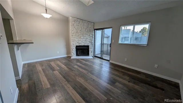 an empty room with wooden floor fireplace and windows