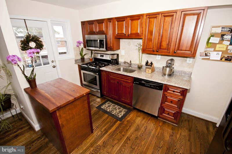 5512 Channing Road Baltimore, MD 21229 - Photo 11 of 29 a kitchen with stainless steel appliances granite countertop a refrigerator a sink dishwasher a stove and white countertops with wooden floor