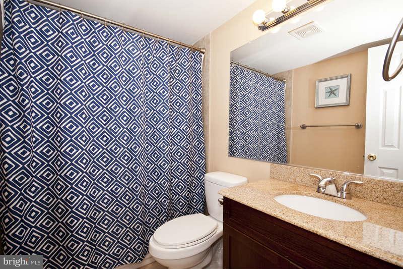 5512 Channing Road Baltimore, MD 21229 - Photo 20 of 29 a bathroom with a granite countertop toilet a sink and a mirror