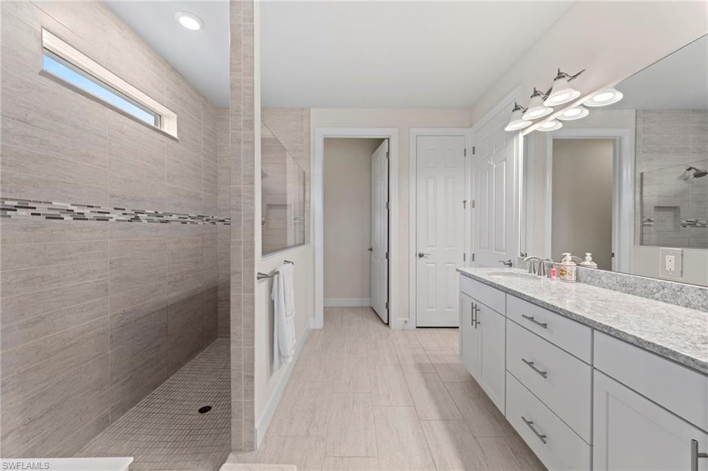 10530 Jackson Square Drive Estero, FL 33928 - Photo 24 of 48 a spacious bathroom with a double vanity sink a large mirror and shower