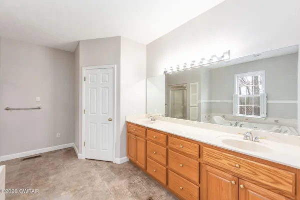 a spacious bathroom with double vanity sink a mirror and a shower