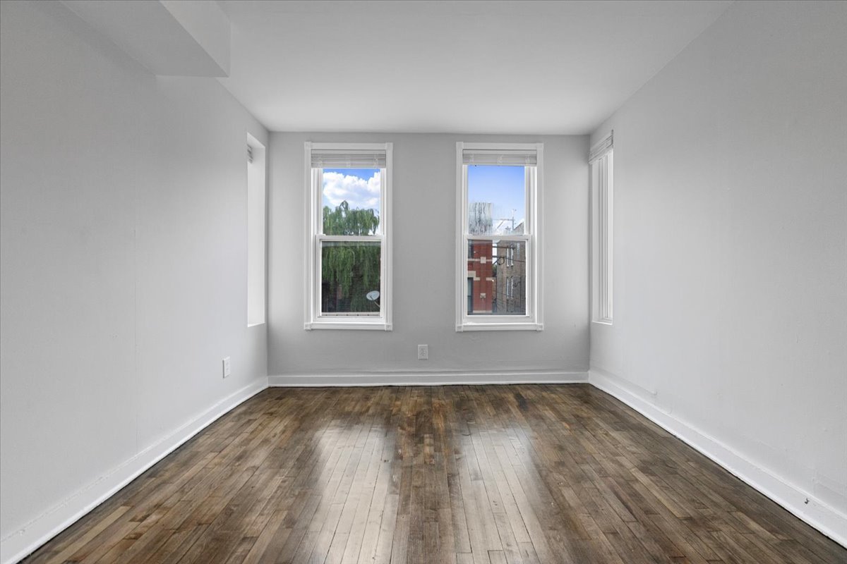 1849 West Augusta Boulevard, Unit 3 Chicago, IL 60622 - Photo 7 of 11 an empty room with wooden floor and windows