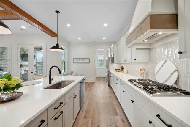 a large kitchen with stainless steel appliances a sink a stove and a wooden floors