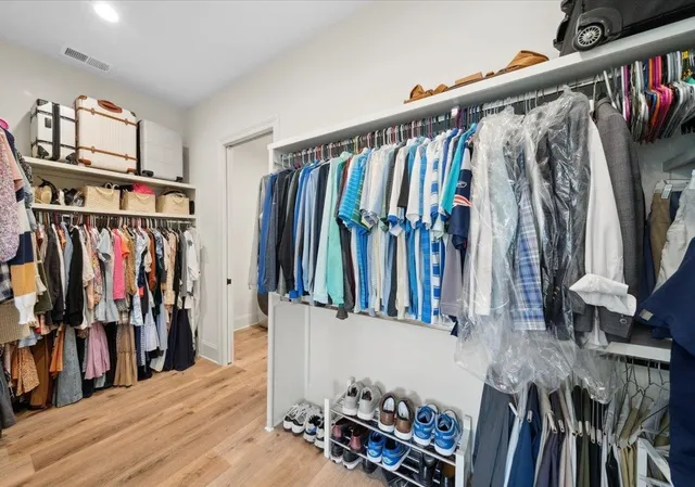 a view of walk in closet with clothes and shoes