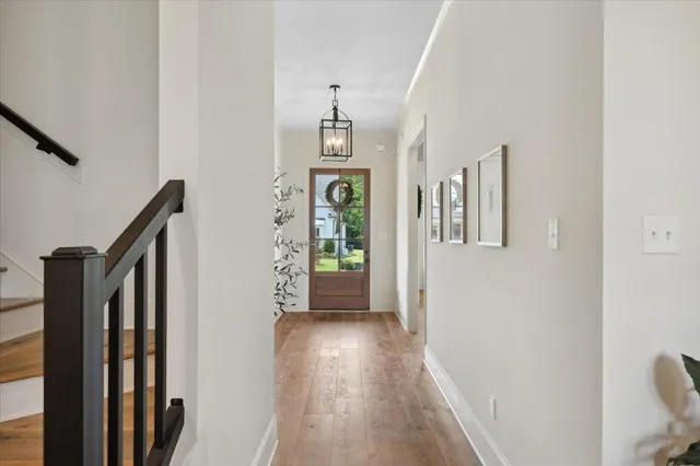 a view of a hallway to a livingroom with wooden floor and stairs