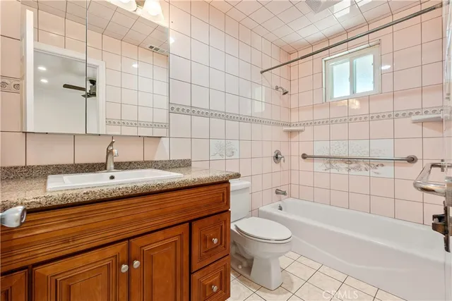 a bathroom with a granite countertop bathtub sink vanity mirror and toilet
