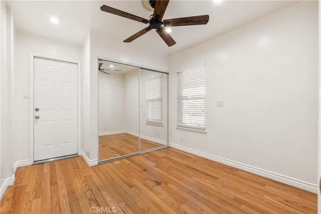 an empty room with wooden floor fan and windows