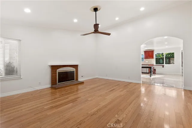 a view of empty room with wooden floor and kitchen view