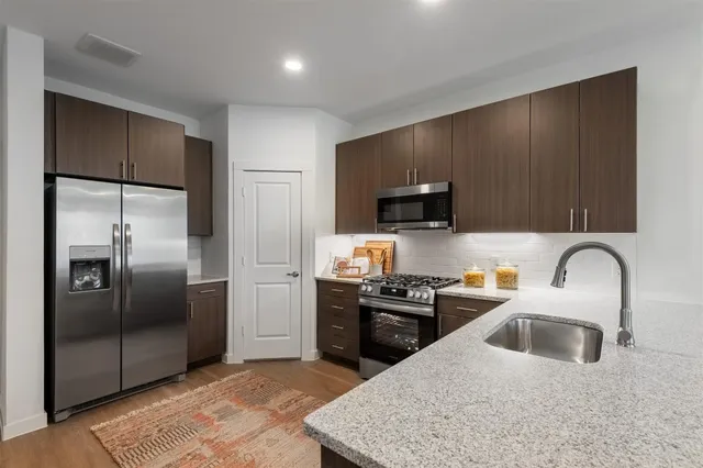 a kitchen with stainless steel appliances granite countertop a sink a stove and refrigerator