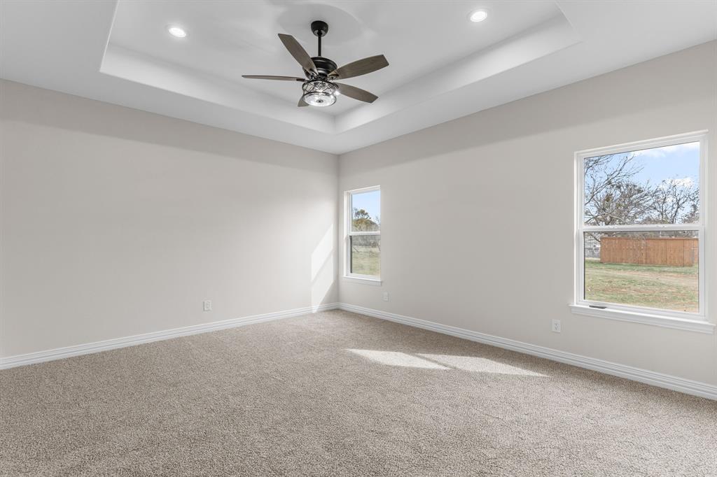 4695 Sisk Road Wichita Falls, TX 76310 - Photo 16 of 32 Carpeted empty room featuring ceiling fan and a tray ceiling