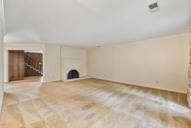 a view of an empty room with a fireplace and a window