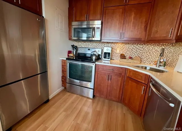 a kitchen with stainless steel appliances granite countertop a refrigerator stove a sink and dishwasher with wooden floor