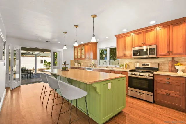 a kitchen with stainless steel appliances granite countertop a stove top oven a sink dishwasher and white cabinets with wooden floor