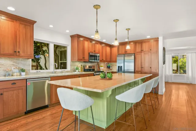 a large kitchen with kitchen island a large window and chairs