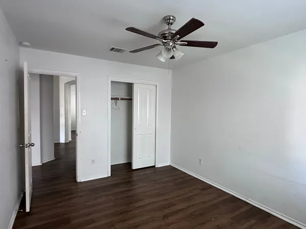 an empty room with wooden floor and a ceiling fan