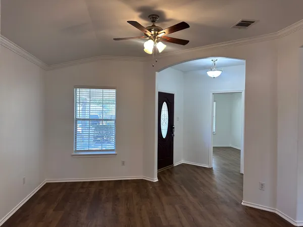 an empty room with wooden floor chandelier fan and windows