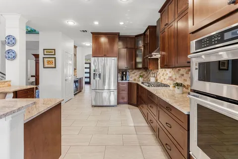 a kitchen with stainless steel appliances granite countertop a stove a sink and a refrigerator