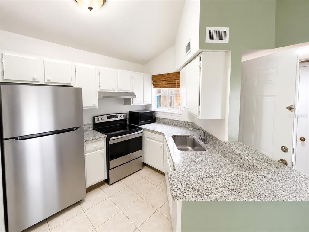 1908 Lake Atriums Circle, Unit 9 Orlando, FL 32839 - Photo 2 of 11 a kitchen with a refrigerator sink and stove