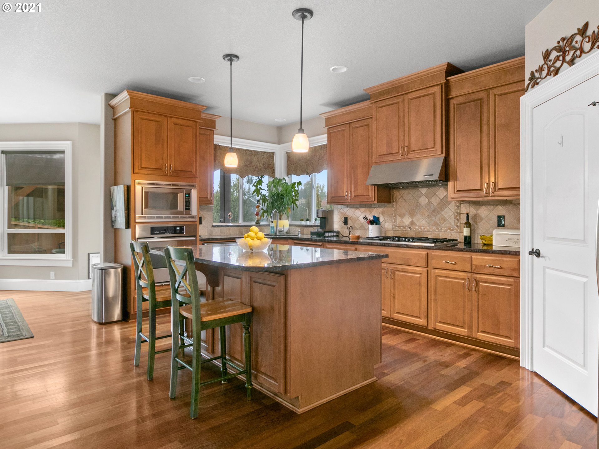 14741 Southeast Badger Creek Road Happy Valley, OR 97086 - Photo 10 of 32 a kitchen with stainless steel appliances granite countertop a stove top oven a sink a dining table and chairs with wooden floor