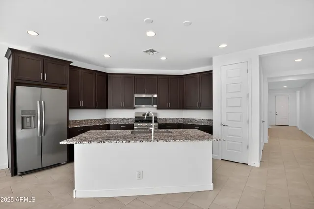 a kitchen with kitchen island a counter top space cabinets and stainless steel appliances