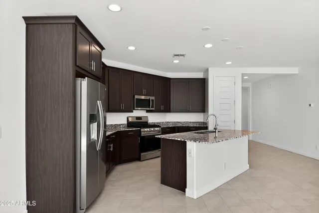 a kitchen with stainless steel appliances granite countertop a stove top oven a sink and a refrigerator