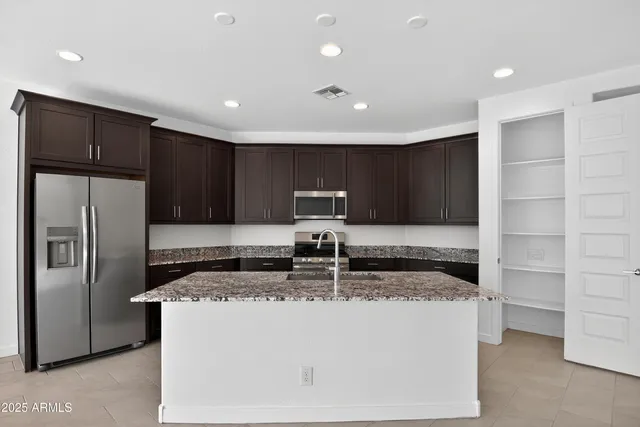 a kitchen with kitchen island granite countertop stainless steel appliances a refrigerator a stove a microwave and cabinets