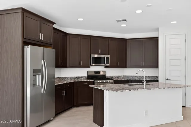a kitchen with a sink a stove a refrigerator and black cabinets