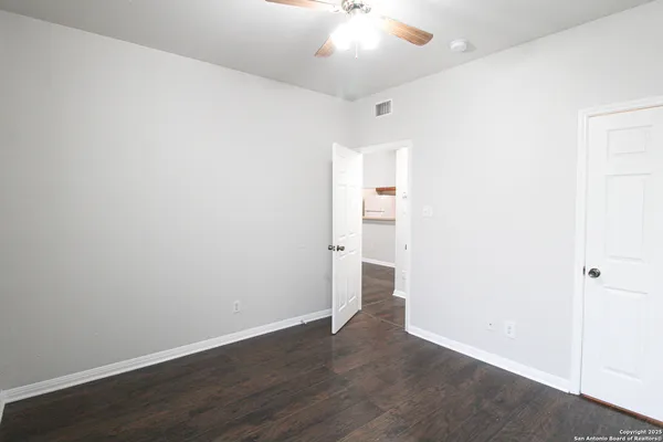 an empty room with wooden floor and a ceiling fan
