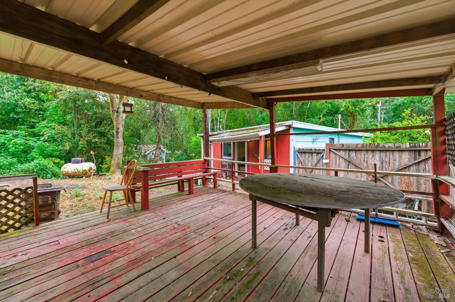 9489 Rio Vista Road Forestville, CA 95436 - Photo 9 of 32 a view of a patio with table and chairs a barbeque with wooden floor and roof with a barbeque grill