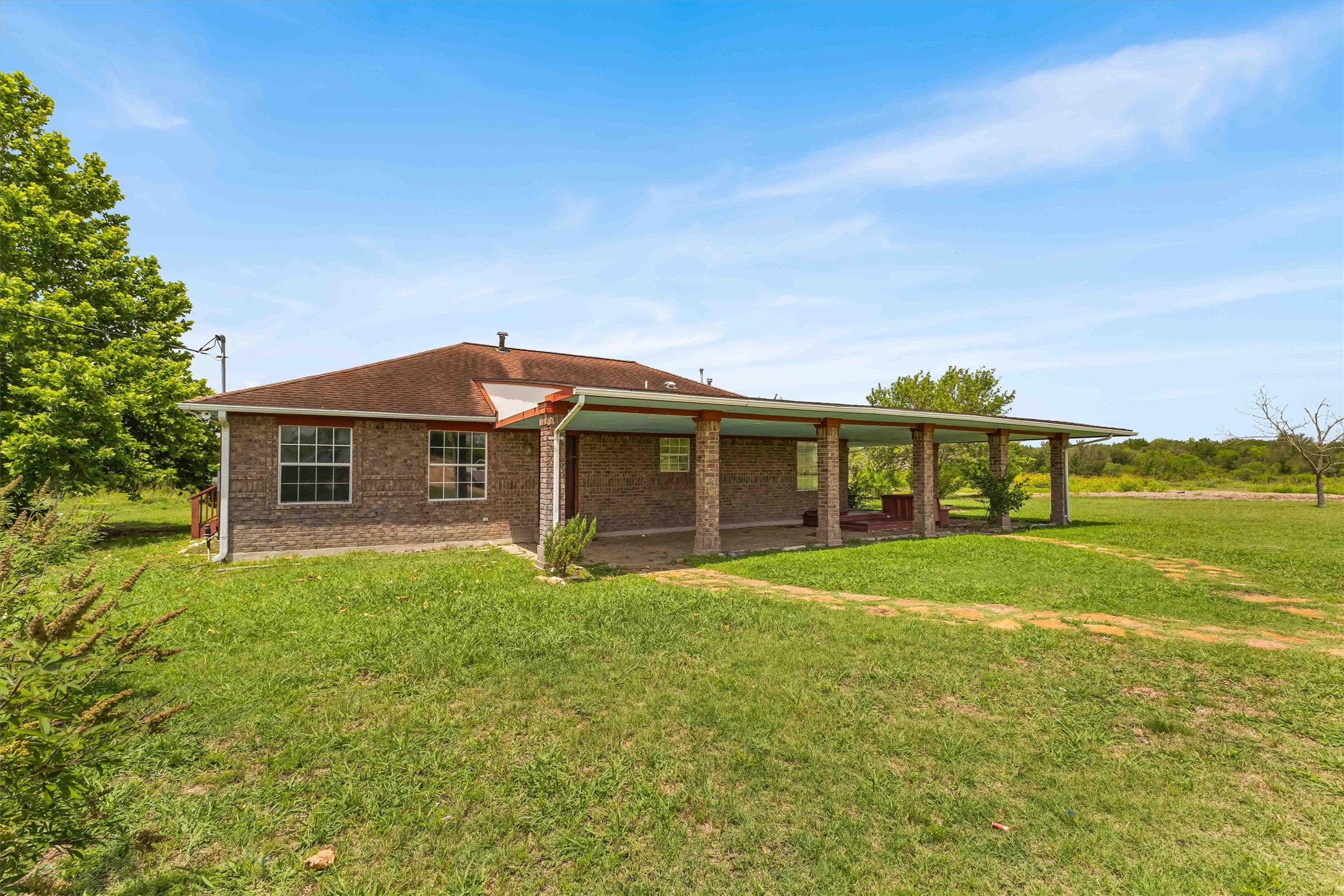 12212 Ballerstedt Road Elgin, TX 78621 - Photo 3 of 39 Back of property featuring a lawn, a patio area, brick siding, and roof with shingles