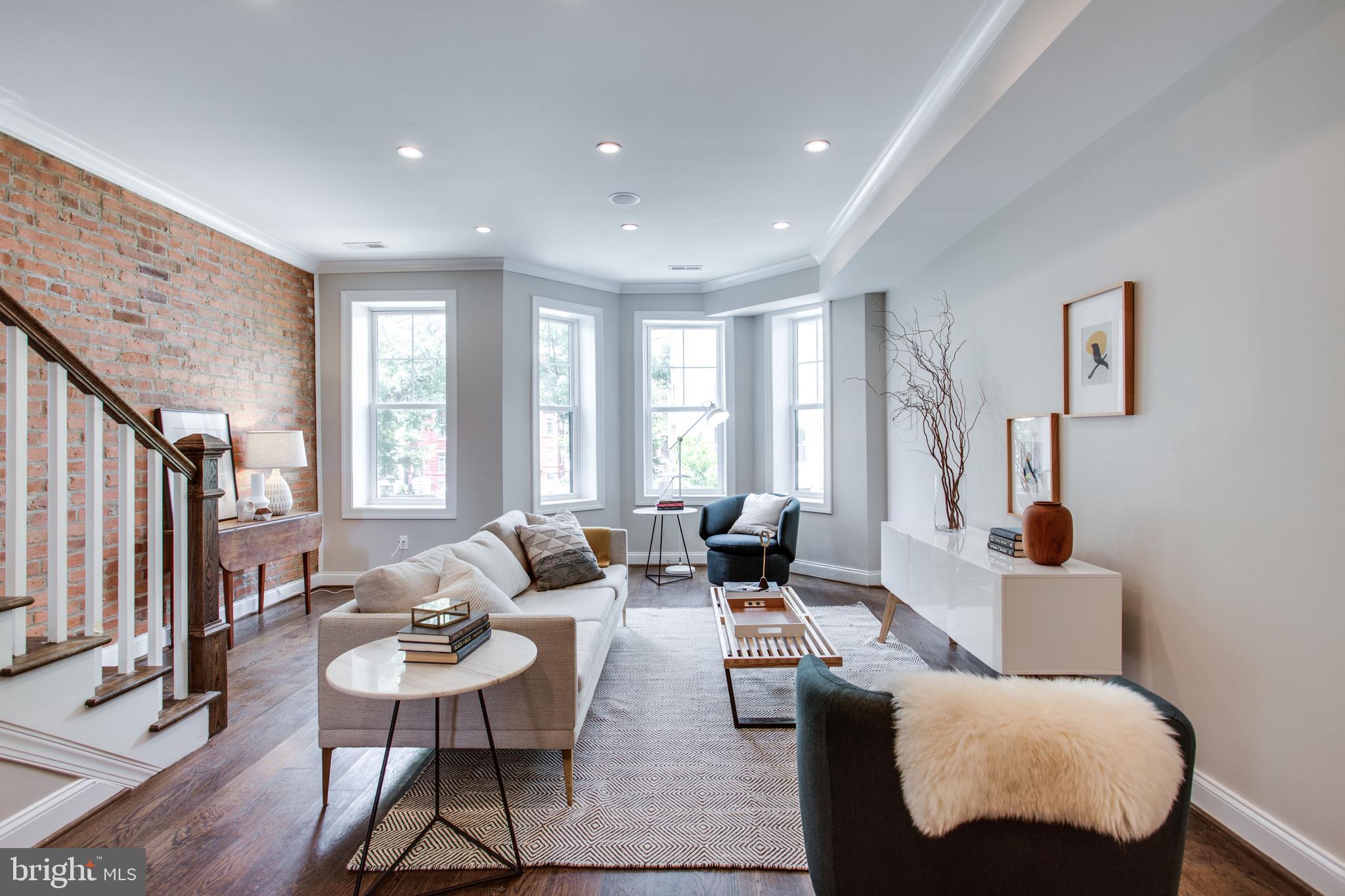 Living room with bay window & exposed brick walls