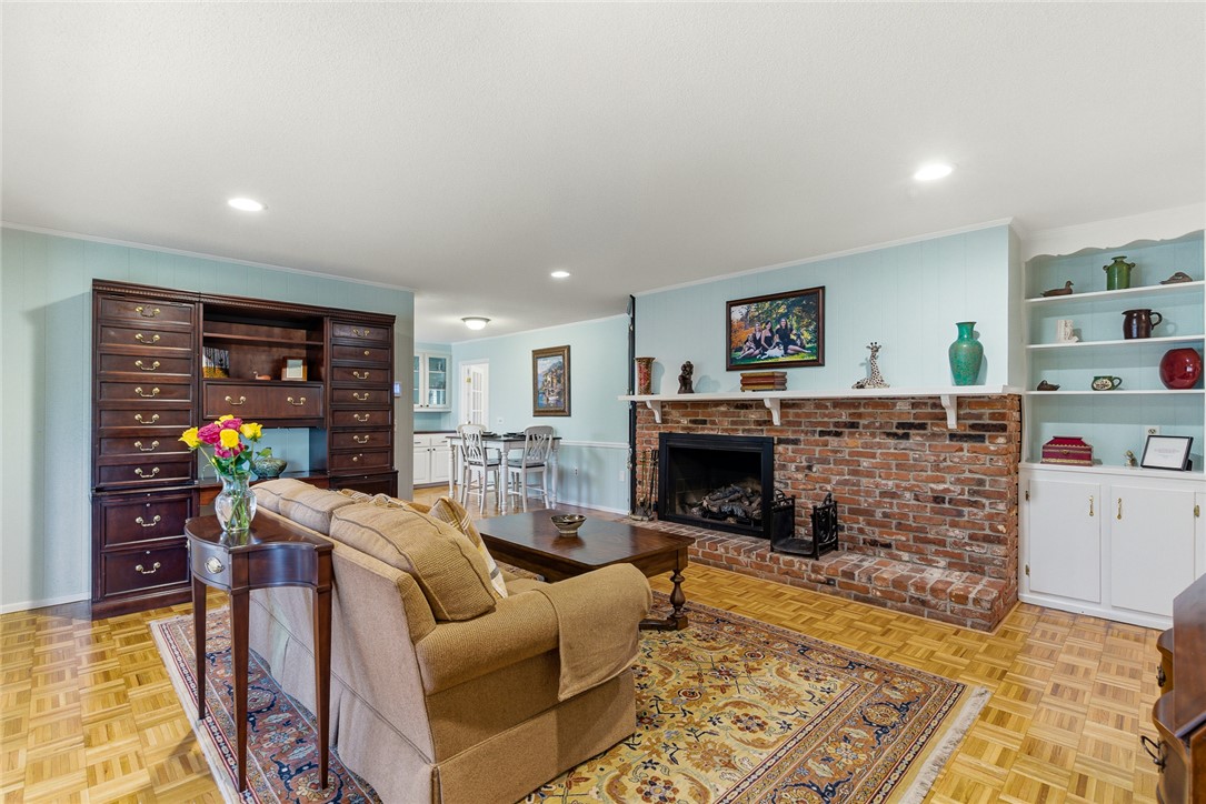 106 Cherokee Circle Anderson, SC 29621 - Photo 20 of 47 An inviting living room features a brick fireplace, built-in shelving, and warm wood flooring.