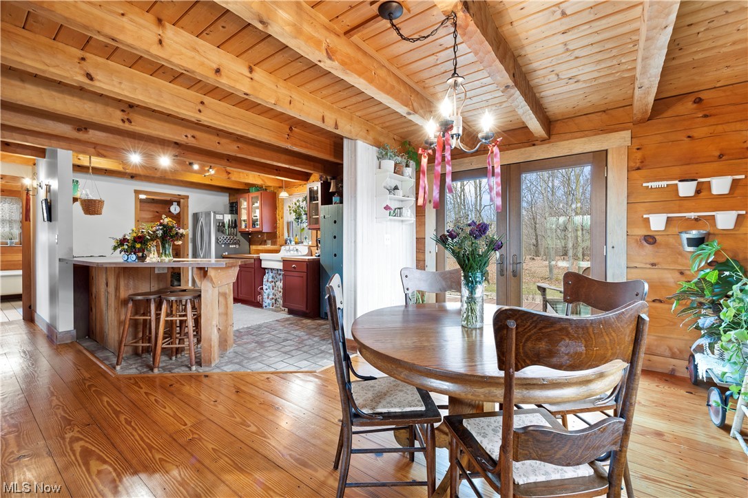 9485 Stone Road Litchfield, OH 44253 - Photo 14 of 50 Tiled dining area featuring wooden walls, a chandelier, beam ceiling, and wood ceiling