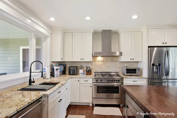 a kitchen with granite countertop a sink stainless steel appliances and white cabinets