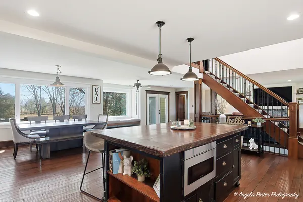 a dining room with wooden floor a chandelier a glass table and chairs