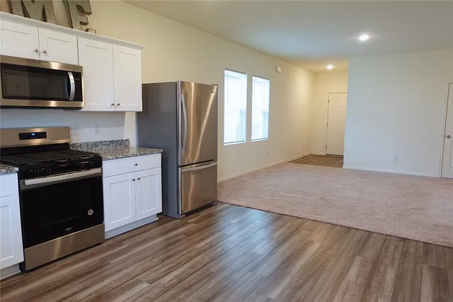 a kitchen with granite countertop a stove a sink and a microwave