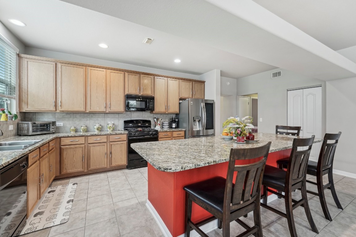 1373 Nevarez Kyle, TX 78640 - Photo 10 of 39 a kitchen with stainless steel appliances granite countertop a table chairs sink refrigerator and cabinets