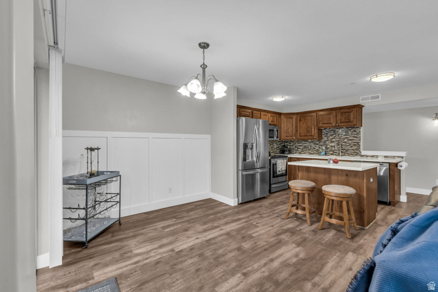 905 South Main Street, Unit G Layton, UT 84041 - Photo 7 of 36 Kitchen with a chandelier, a center island, brown cabinetry, appliances with stainless steel finishes, and hanging light fixtures